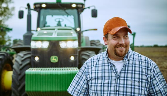 Smiling Farm Funders customer in front of tractor after a hard day of planting