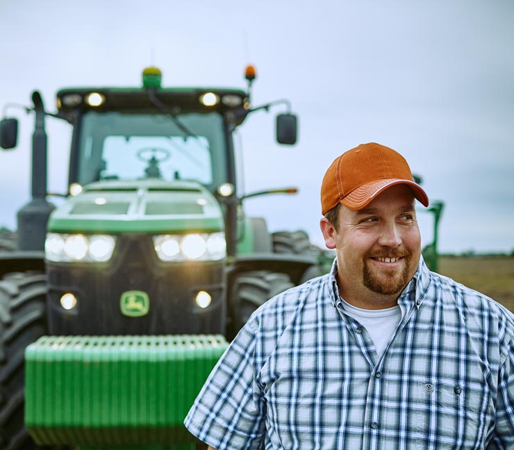 Smiling Farm Funders customer in front of tractor after a hard day of planting 